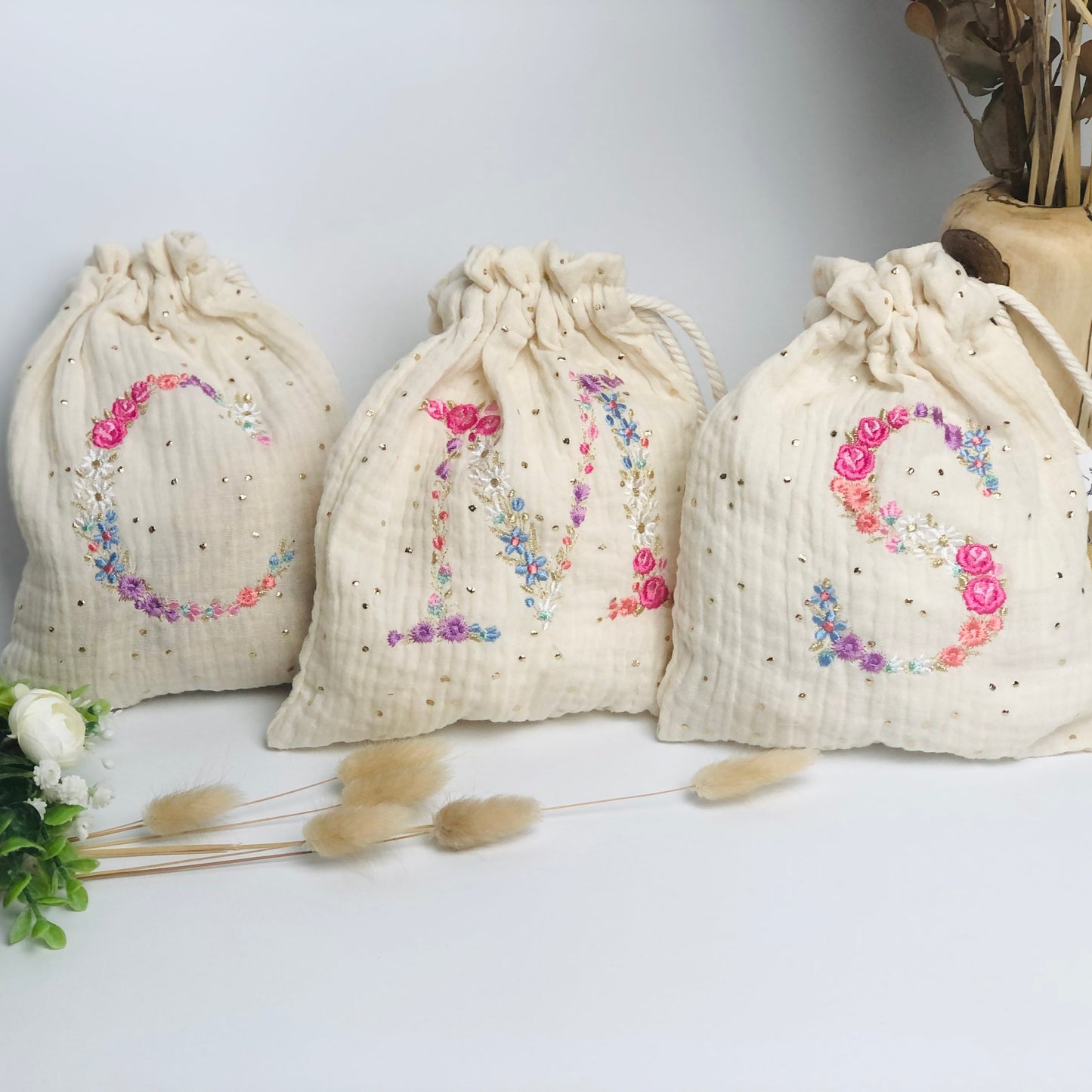 Cream-colored pouch with a golden floral initial