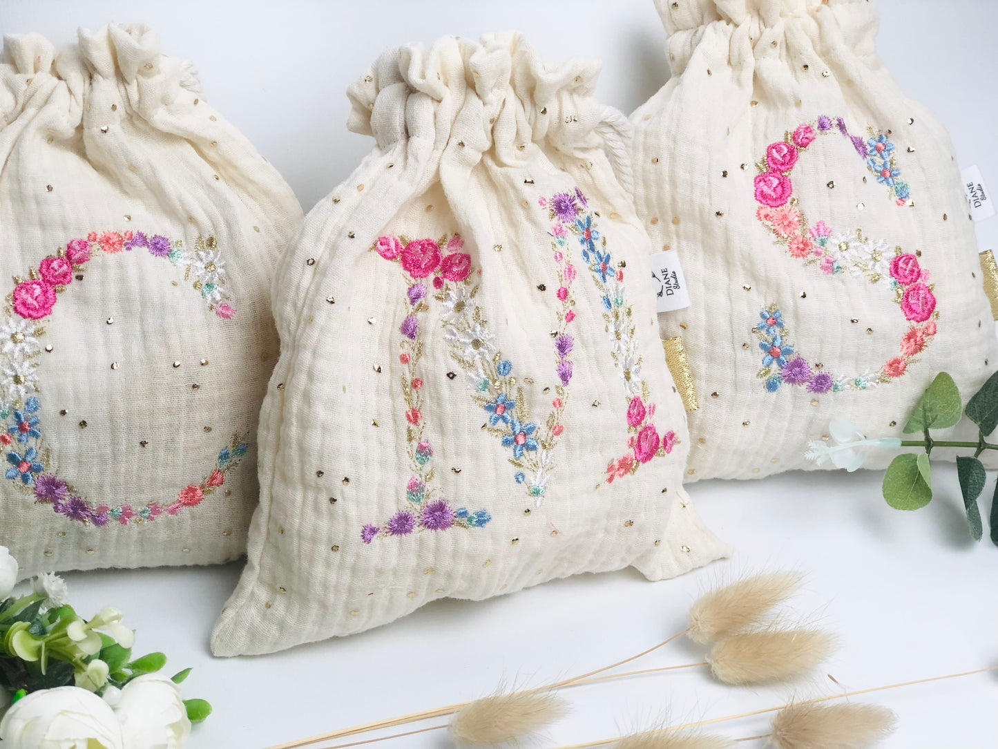 Cream-colored pouch with a golden floral initial