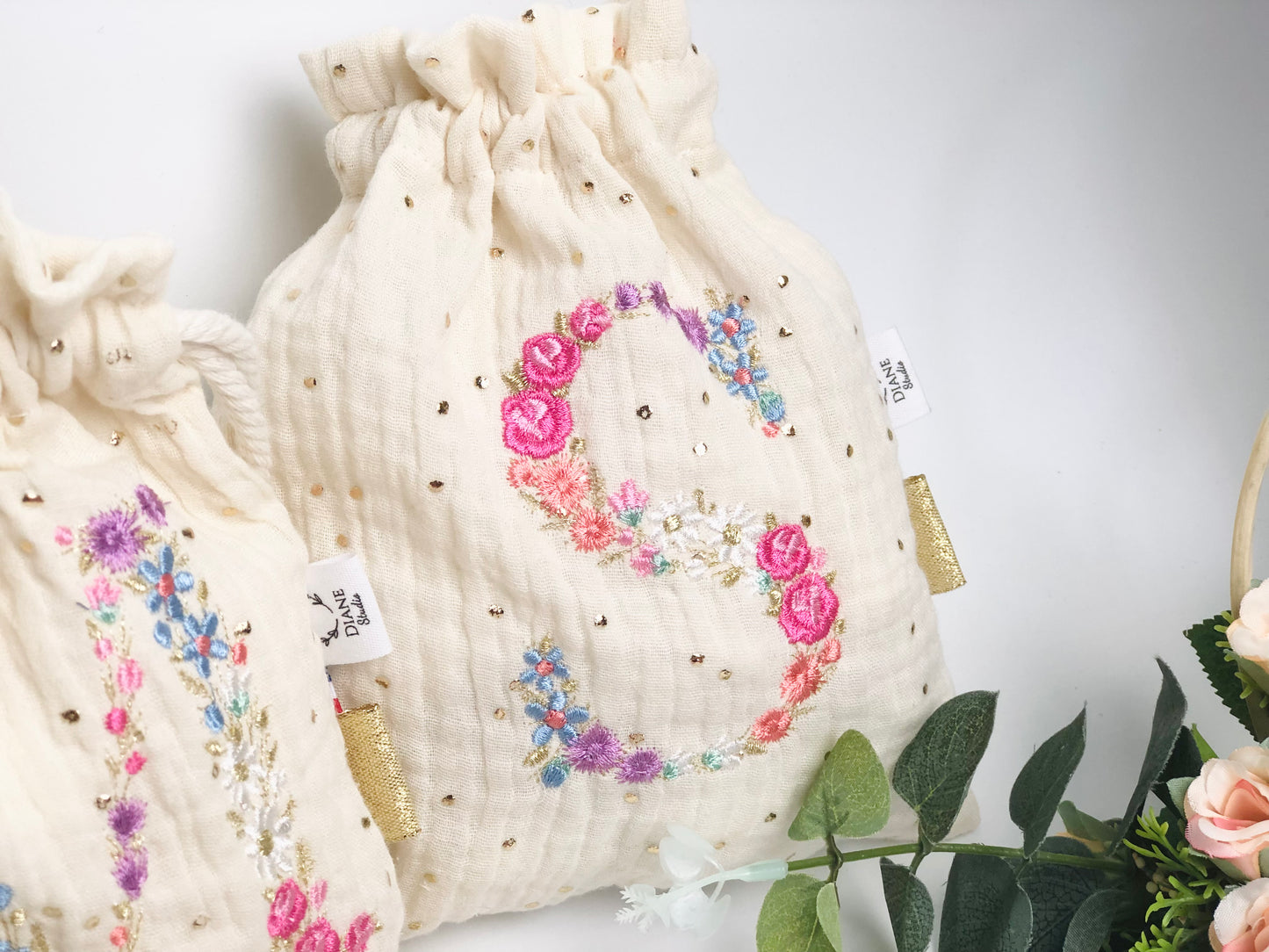Cream-colored pouch with a golden floral initial