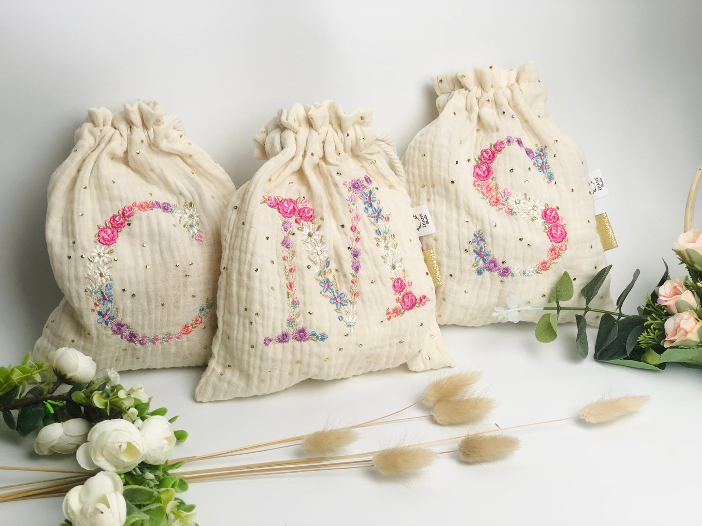 Cream-colored pouch with a golden floral initial