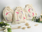 Cream-colored pouch with a golden floral initial