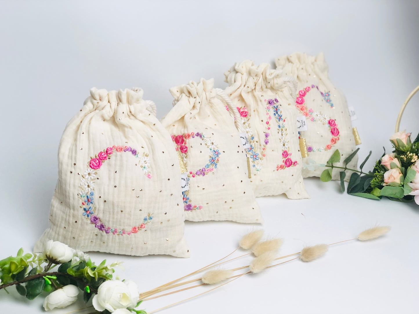 Cream-colored pouch with a golden floral initial
