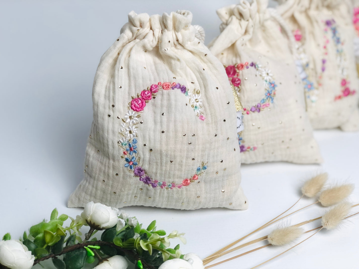 Cream-colored pouch with a golden floral initial