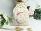 Cream-colored pouch with a golden floral initial