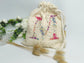 Cream-colored pouch with a golden floral initial