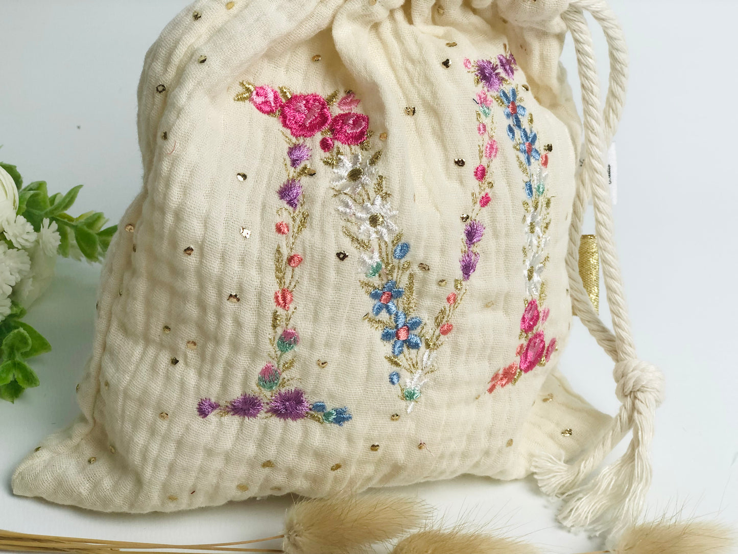 Cream-colored pouch with a golden floral initial
