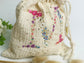 Cream-colored pouch with a golden floral initial