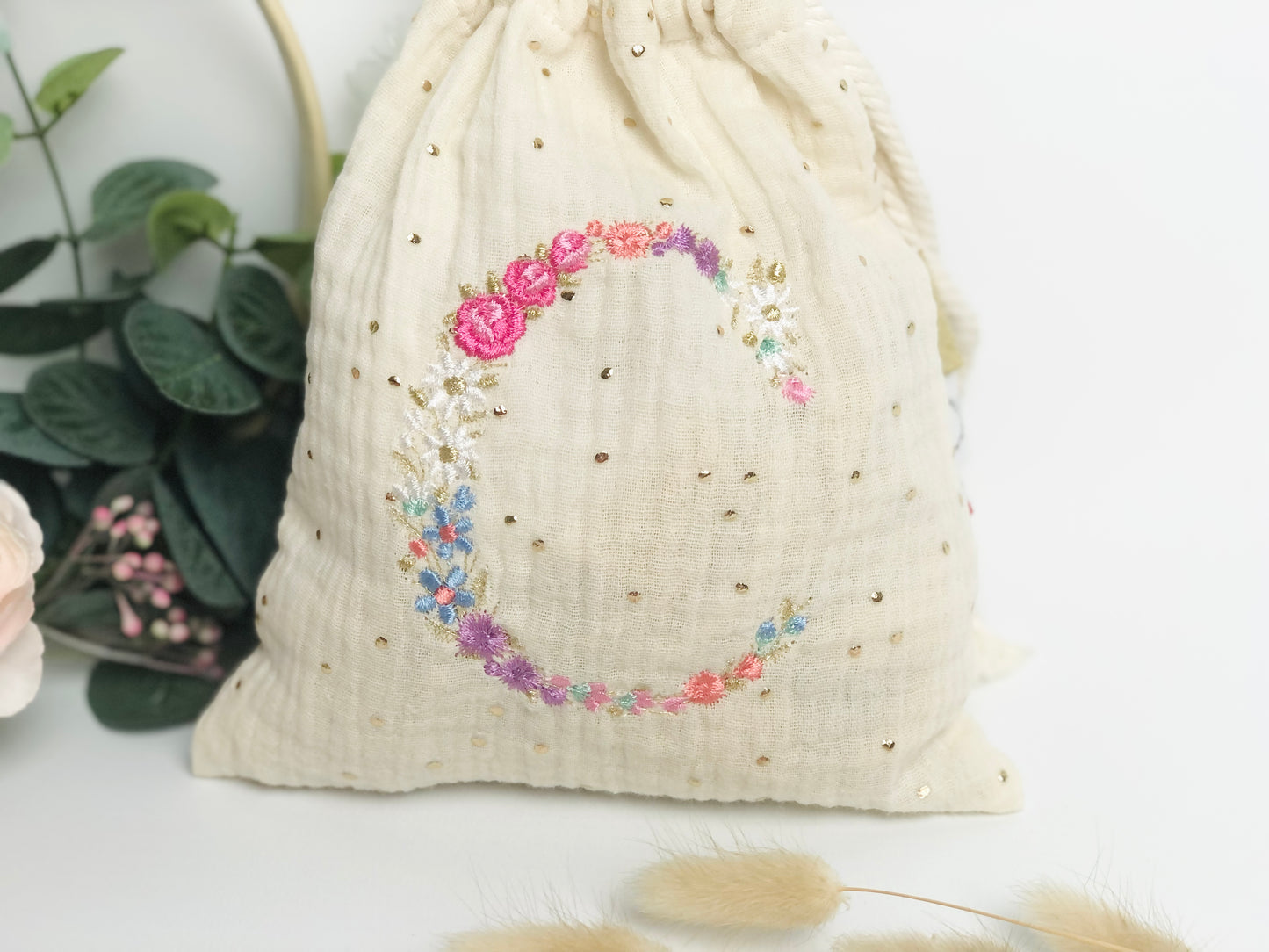 Cream-colored pouch with a golden floral initial