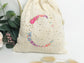 Cream-colored pouch with a golden floral initial